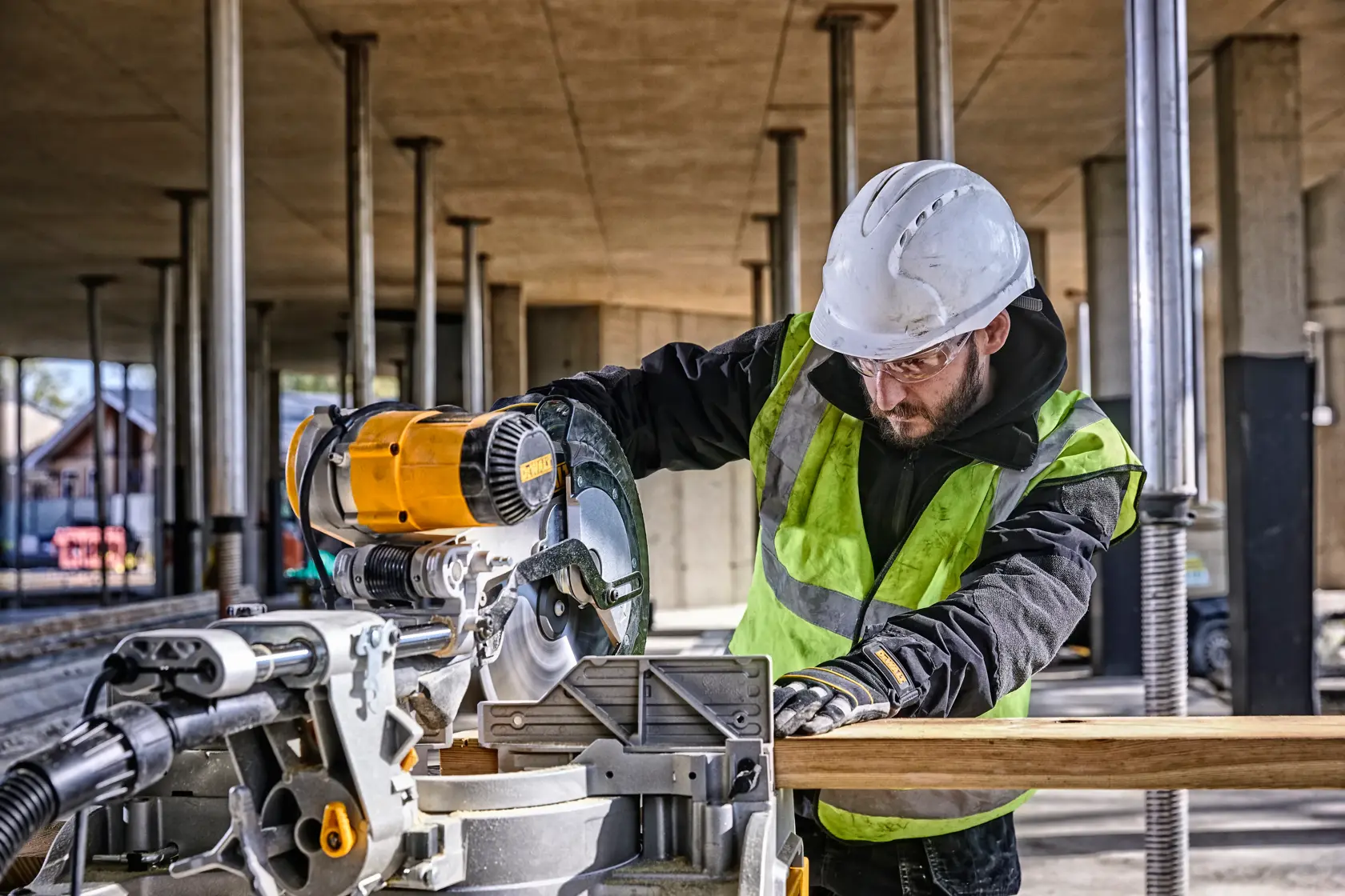 DEWALT DWS780, DWS780KIT miter saw used by worker cutting wood at construction site. Photography category.