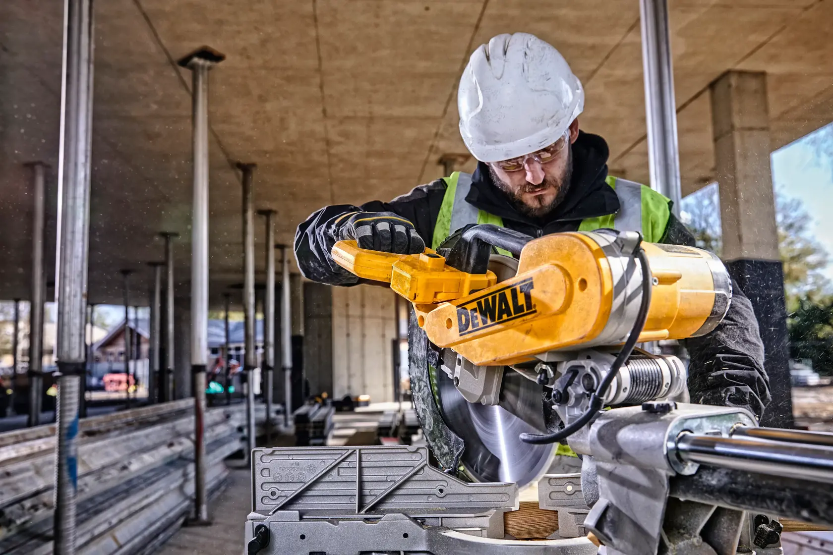 DEWALT DWS780, DWS780KIT saw in use at construction site, worker with helmet and vest. Photography category.