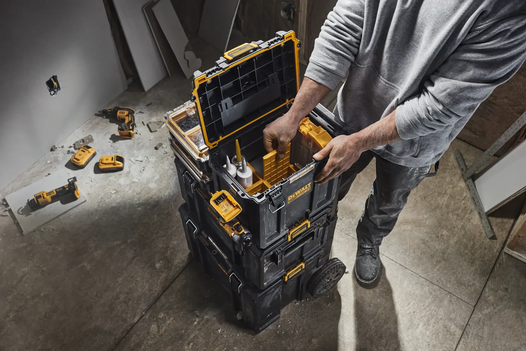 A DEWALT ToughSystem toolbox with its lid open, showing various tools and accessories stored inside, including power tools, containers, and a yellow case.