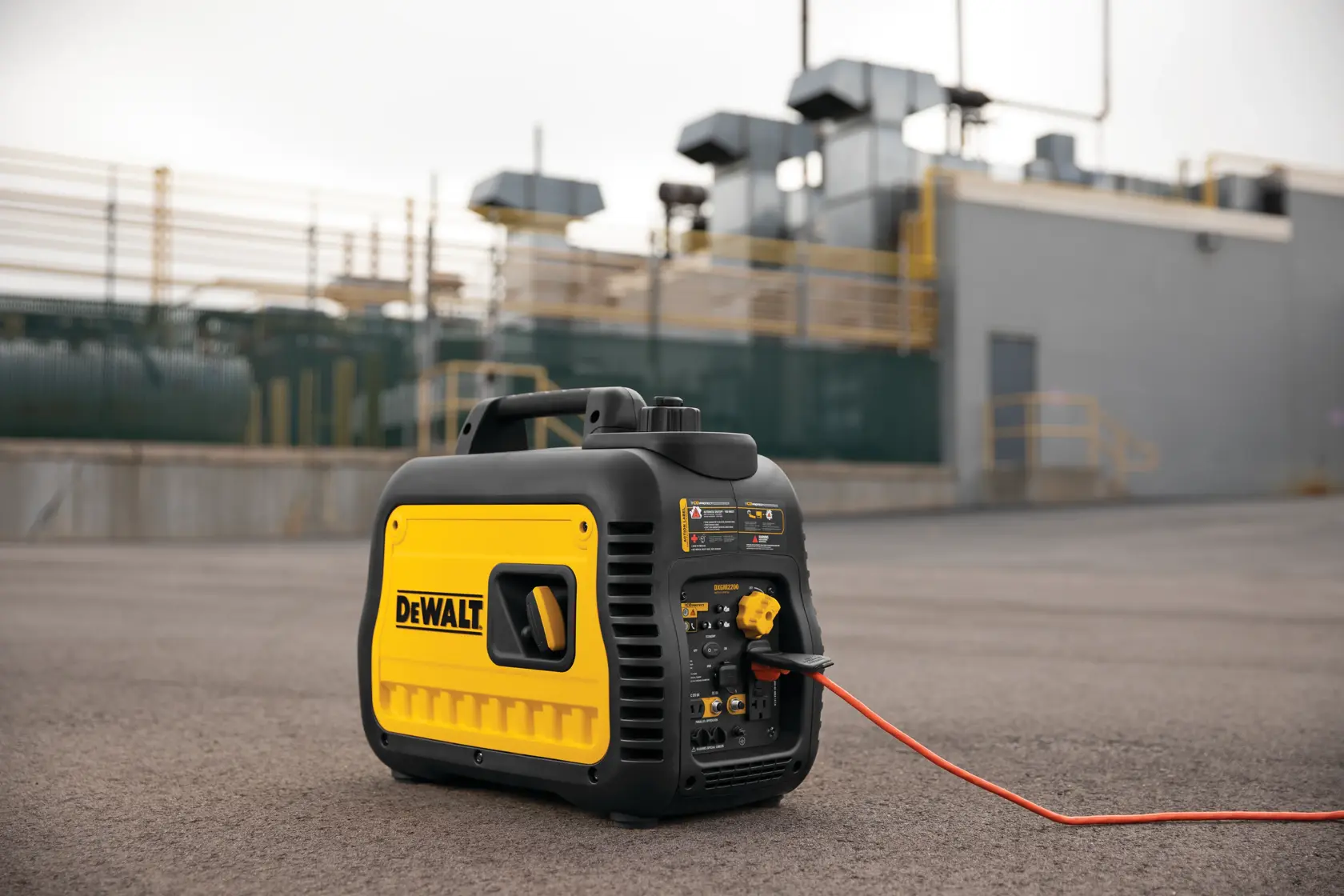 A portable DEWALT generator (model DXGNI2200) is shown outdoors on a paved surface, with an industrial facility in the background. The generator has a yellow and black design and is connected to a red power cord.